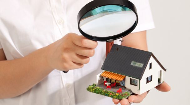 someone using a magnifying glass to inspect a home